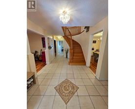 A spacious hallway with a staircase and a chandelier.