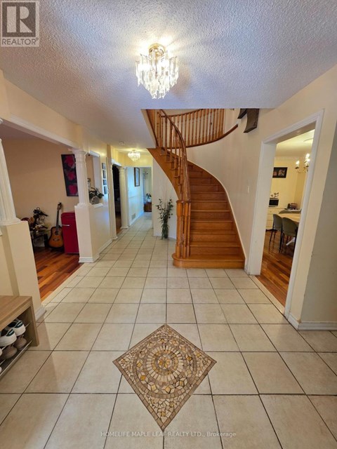 A spacious hallway with a staircase and a chandelier.