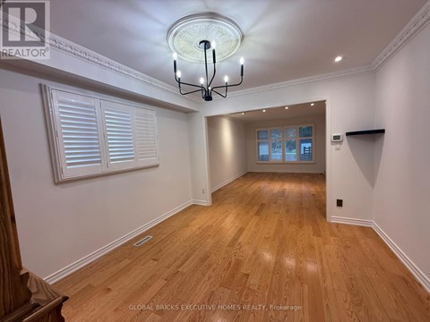 A well-lit room with wooden floors and a chandelier.
