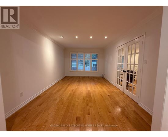 A spacious room with wooden flooring and a large window.
