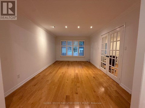 A spacious room with wooden flooring and a large window.