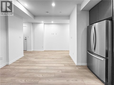 A modern kitchen with a stainless steel refrigerator and wooden flooring.