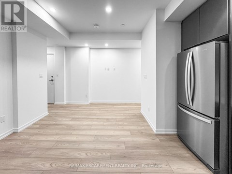 A kitchen with a stainless steel refrigerator and wooden flooring.