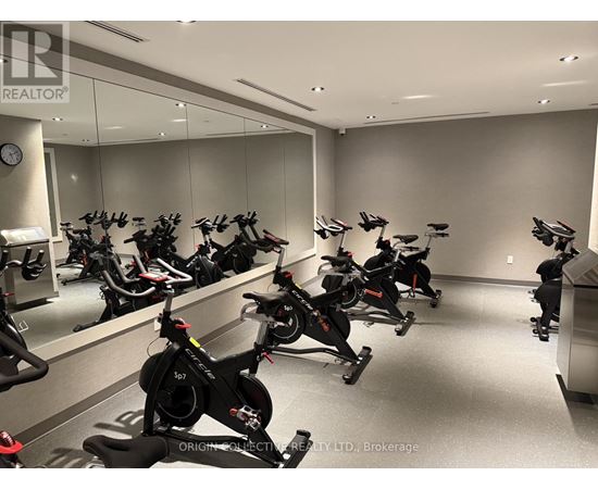 A room full of stationary bikes in front of a mirror.