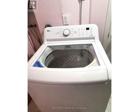 A white LG washing machine is on a pink wall.