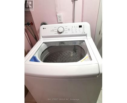 A white LG washing machine is on a pink wall.