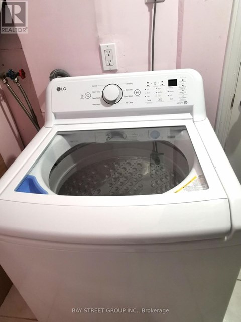 A white LG washing machine is on a pink wall.