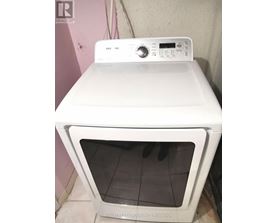 A white Samsung dryer is sitting on top of a white oven.