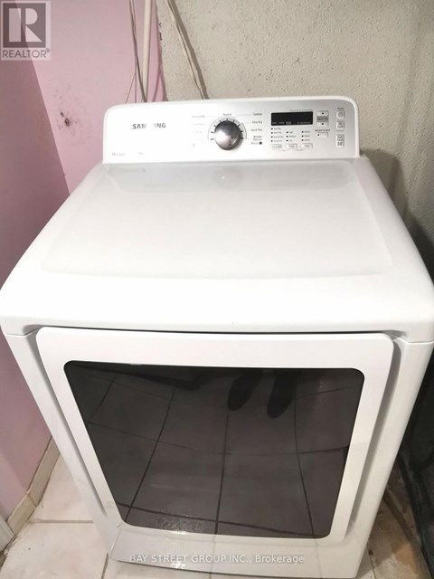 A white Samsung dryer is sitting on top of a white oven.