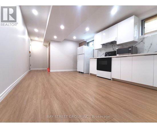 A spacious kitchen with white cabinets and a wooden floor.