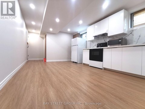 A spacious kitchen with white cabinets and a wooden floor.
