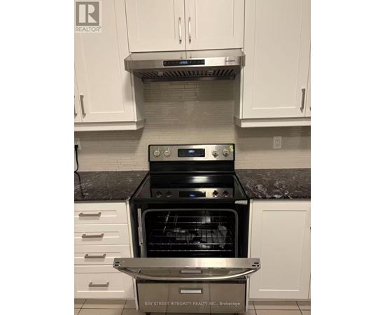 A modern kitchen with a stainless steel oven and white cabinets.