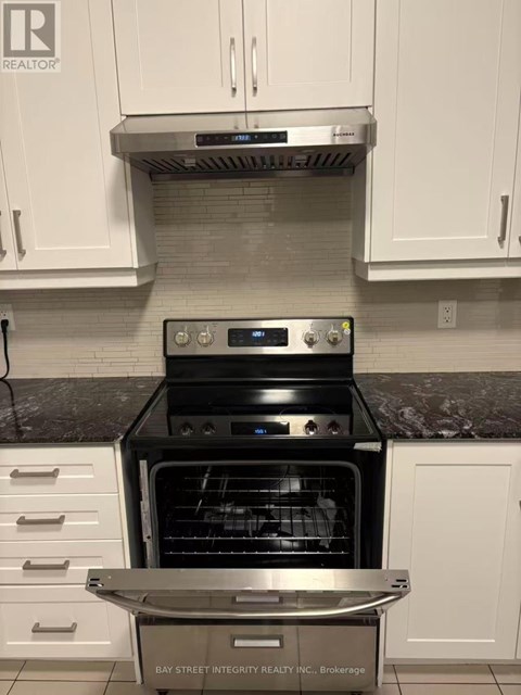 A modern kitchen with a stainless steel oven and white cabinets.