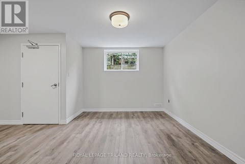 A room with a door and a window with a view of trees and houses.