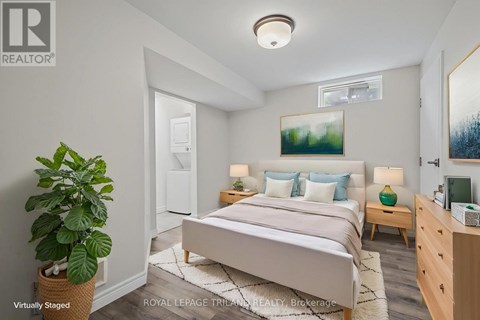 A bedroom with a bed, nightstands, and a plant.