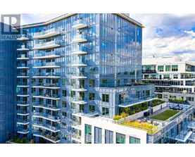 A modern glass building with balconies and a green roof.