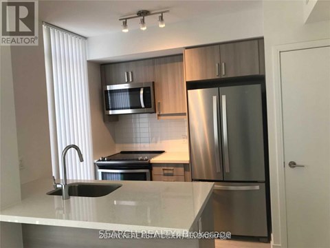 A modern kitchen with stainless steel appliances and a marble countertop.