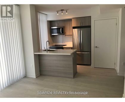 A modern kitchen with a stainless steel refrigerator and a microwave above the stove.