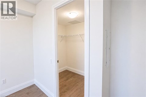 A white bedroom with a doorway leading to another room.