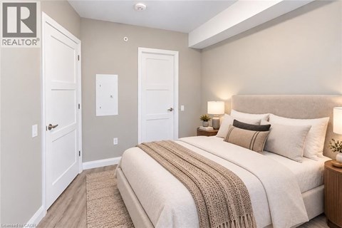 A bedroom with a large bed and a nightstand with a lamp.