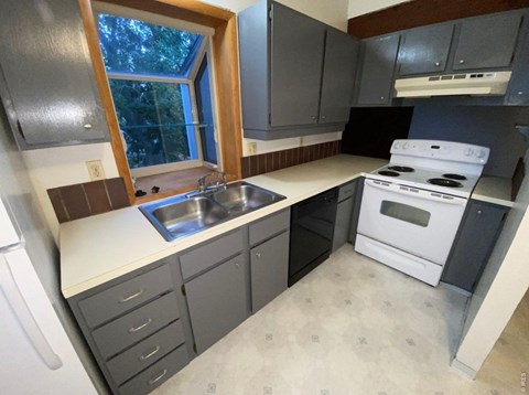 A kitchen with a white stove and a window.