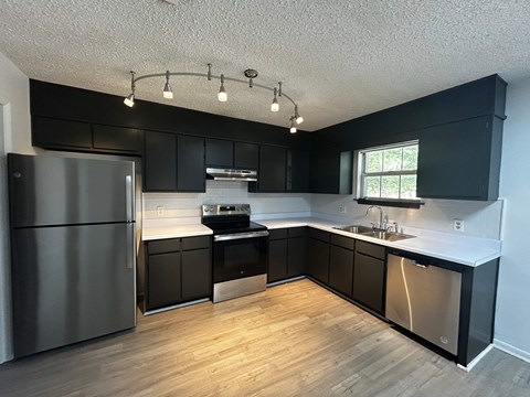 A modern kitchen with a stainless steel refrigerator and black cabinets.