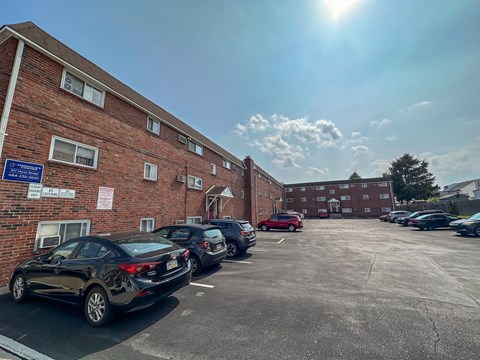 A parking lot with cars parked in front of a brick building on a sunny day.