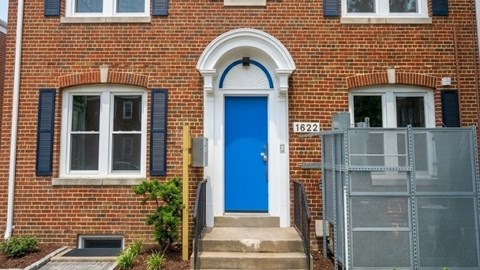 A red brick house with a blue door and a mailbox.