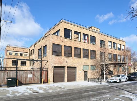 A large brick building with a garage door and a car parked in front.