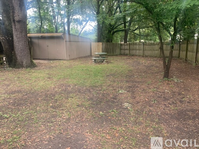 A backyard with a fence, a tree, and a picnic table.