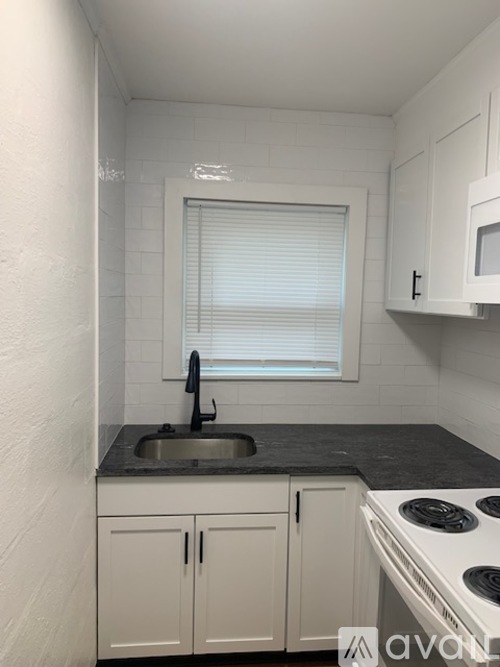 A small kitchen with white cabinets and a black countertop.