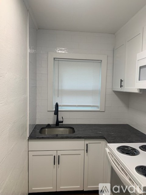 A small kitchen with white cabinets and a black countertop.