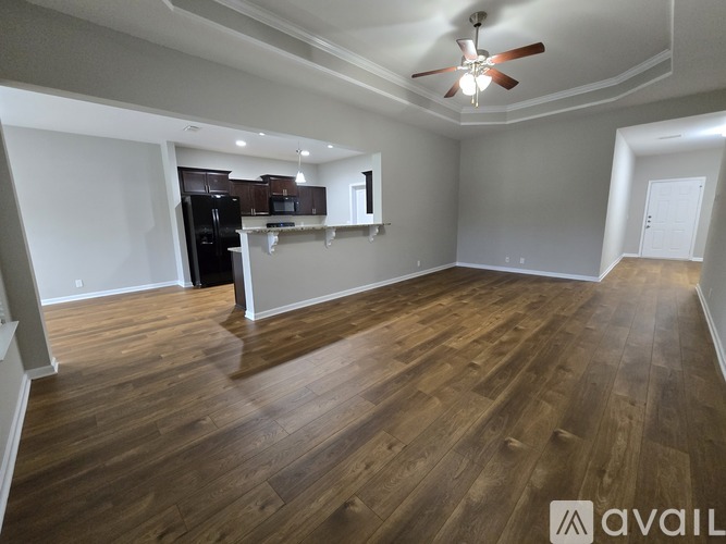 A spacious room with wooden flooring and a ceiling fan.