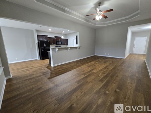 A spacious room with wooden flooring and a ceiling fan.