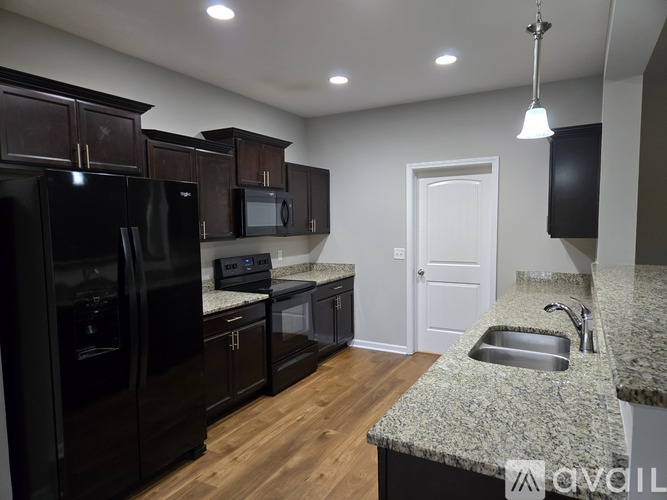 A kitchen with black appliances and a granite countertop.