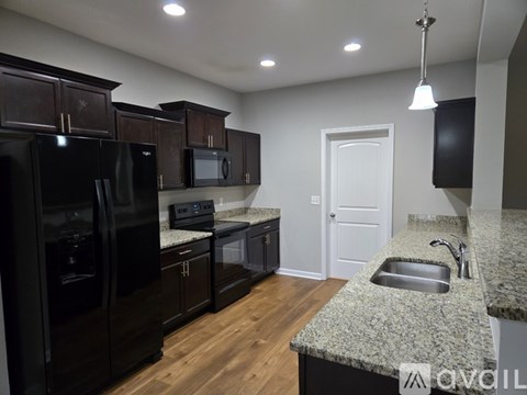 A kitchen with black appliances and a granite countertop.