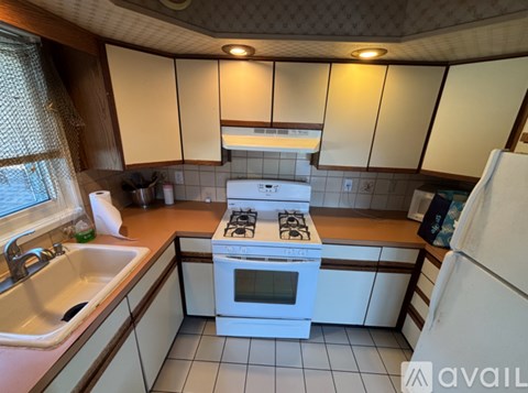 A kitchen with a white stove top oven and a white refrigerator.