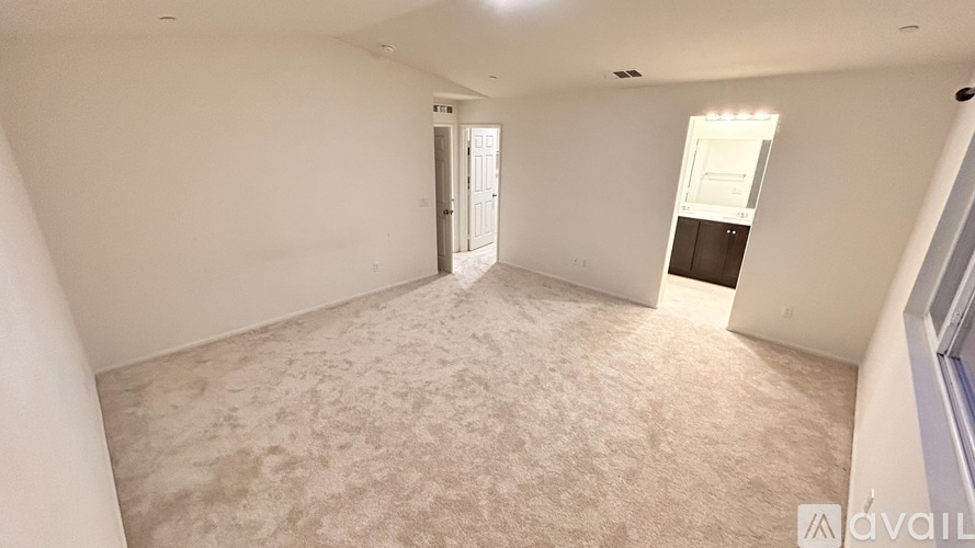 A spacious room with a carpeted floor and a doorway leading to another room.