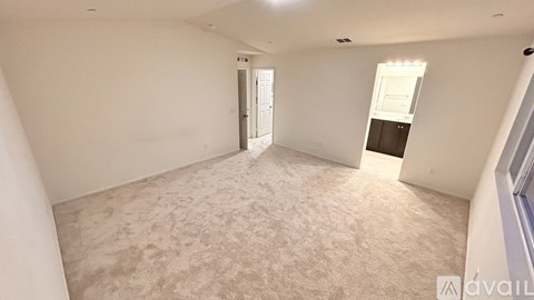 A spacious room with a carpeted floor and a doorway leading to another room.
