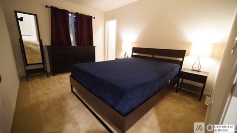 A bedroom with a bed, dresser, and mirror.