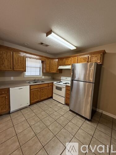 A kitchen with wooden cabinets and a stainless steel refrigerator.