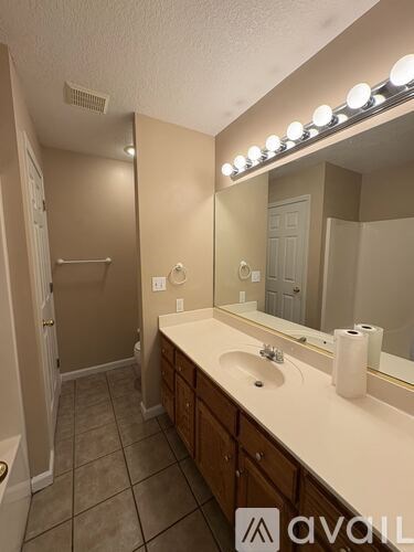A bathroom with a vanity, mirror, and lights.