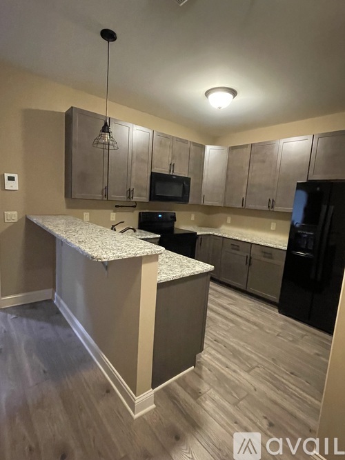 A kitchen with a granite countertop and wooden cabinets.