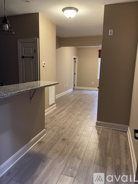 A long hallway with wood floors and a marble counter top.