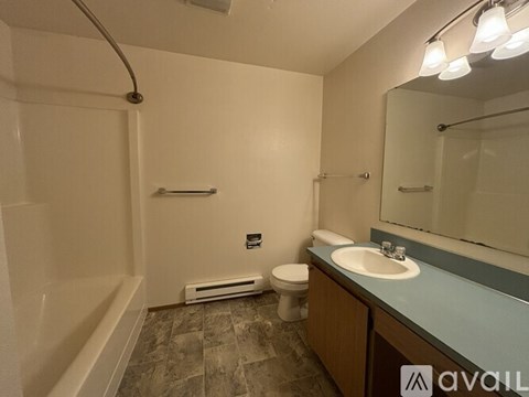 A bathroom with a toilet, sink, mirror, and a shower.