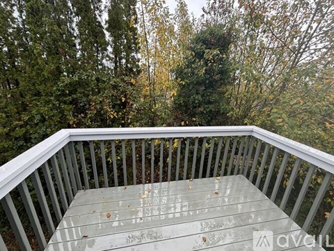 A glass table is on a deck with trees in the background.