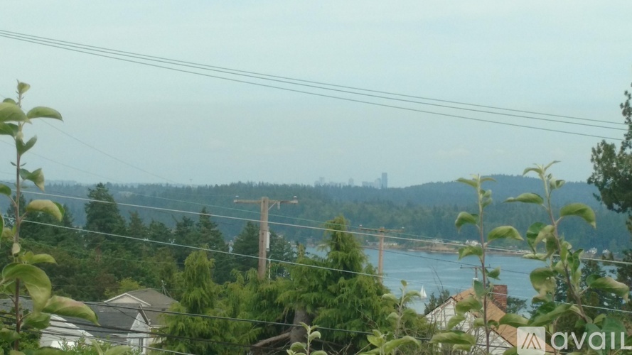 A view of a residential area with houses and trees in the foreground and a bridge in the distance.