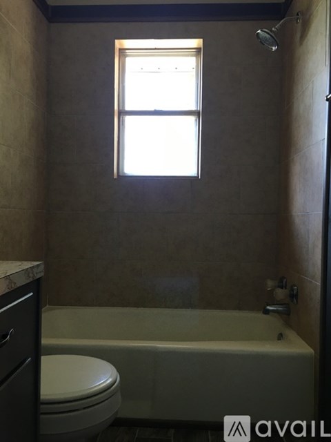 A bathroom with a toilet, tub, and window.