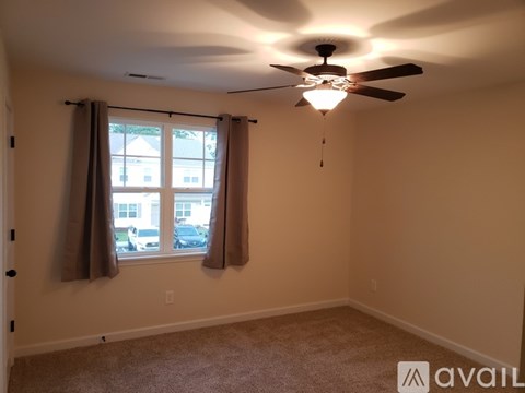 A room with a ceiling fan and a window with curtains.
