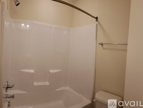 A white shower stall with a glass door and a white toilet.